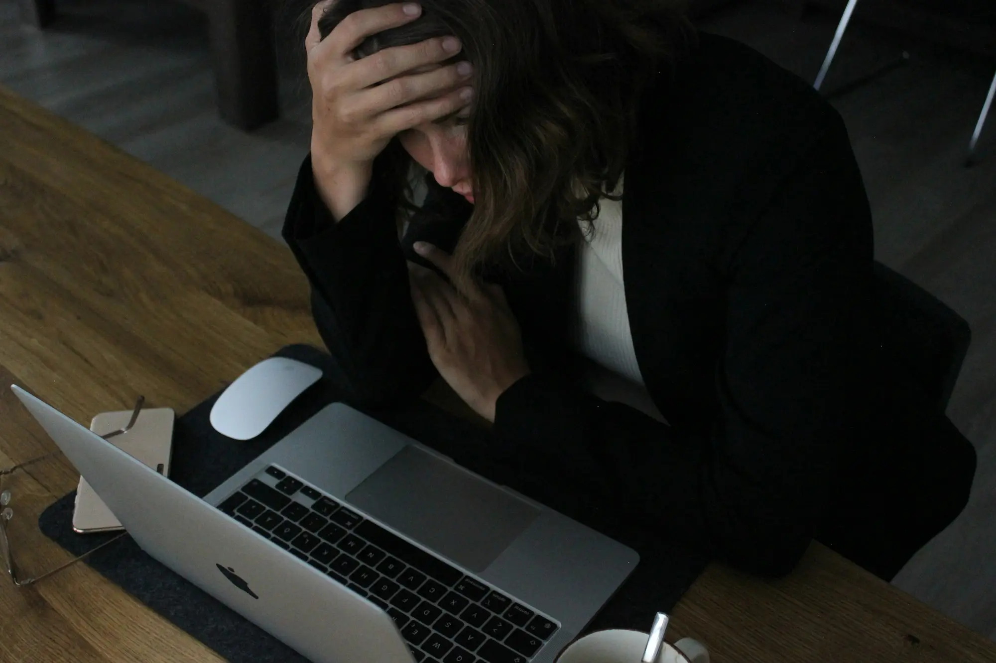 Business owner with her head in her hand at a laptop late at night after a cyber attack locks the company's files