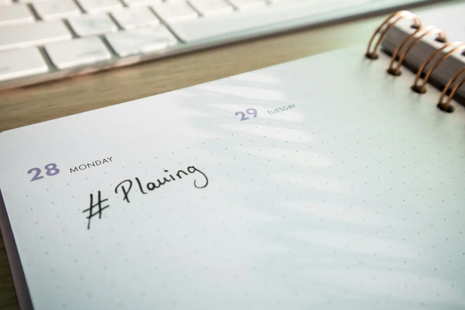 Planner and notepad on a desk beside a keyboard